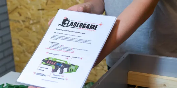 Een pagina met uitleg over lasergamen vastgehouden door een persoon